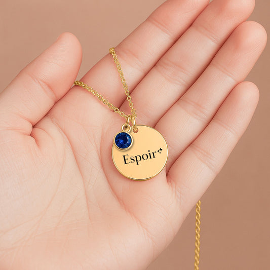 Collier Espoir Maison Tiana, médaillon doré et cristal étoilé, bijou symbolique tenu dans la main.