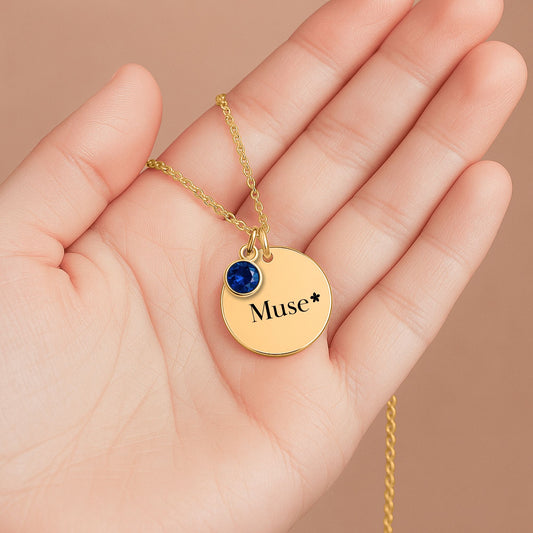 Collier Muse Maison Tiana, médaillon doré et cristal étoilé, bijou symbolique tenu dans la main.